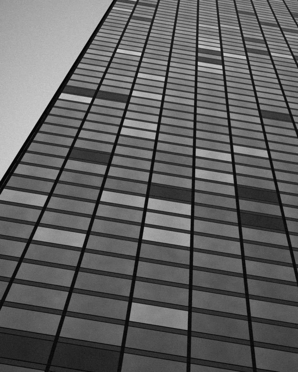 Looking up a glass office tower against a pale sky.